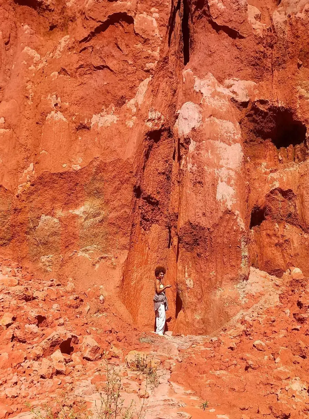 Barranco de terra vermelha em Paraty, com uma pessoa ao pé da parede de solo mostrando a escala