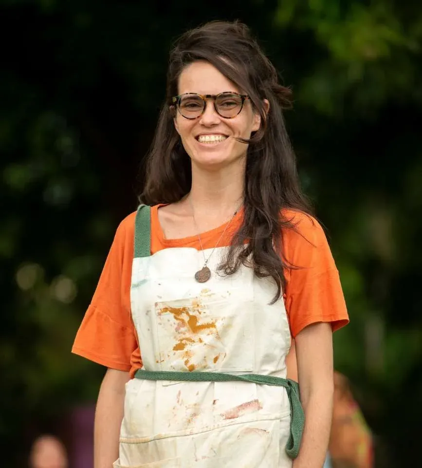 Retrato de Marcela da Terra sorrindo, de avental manchado de pigmento natural