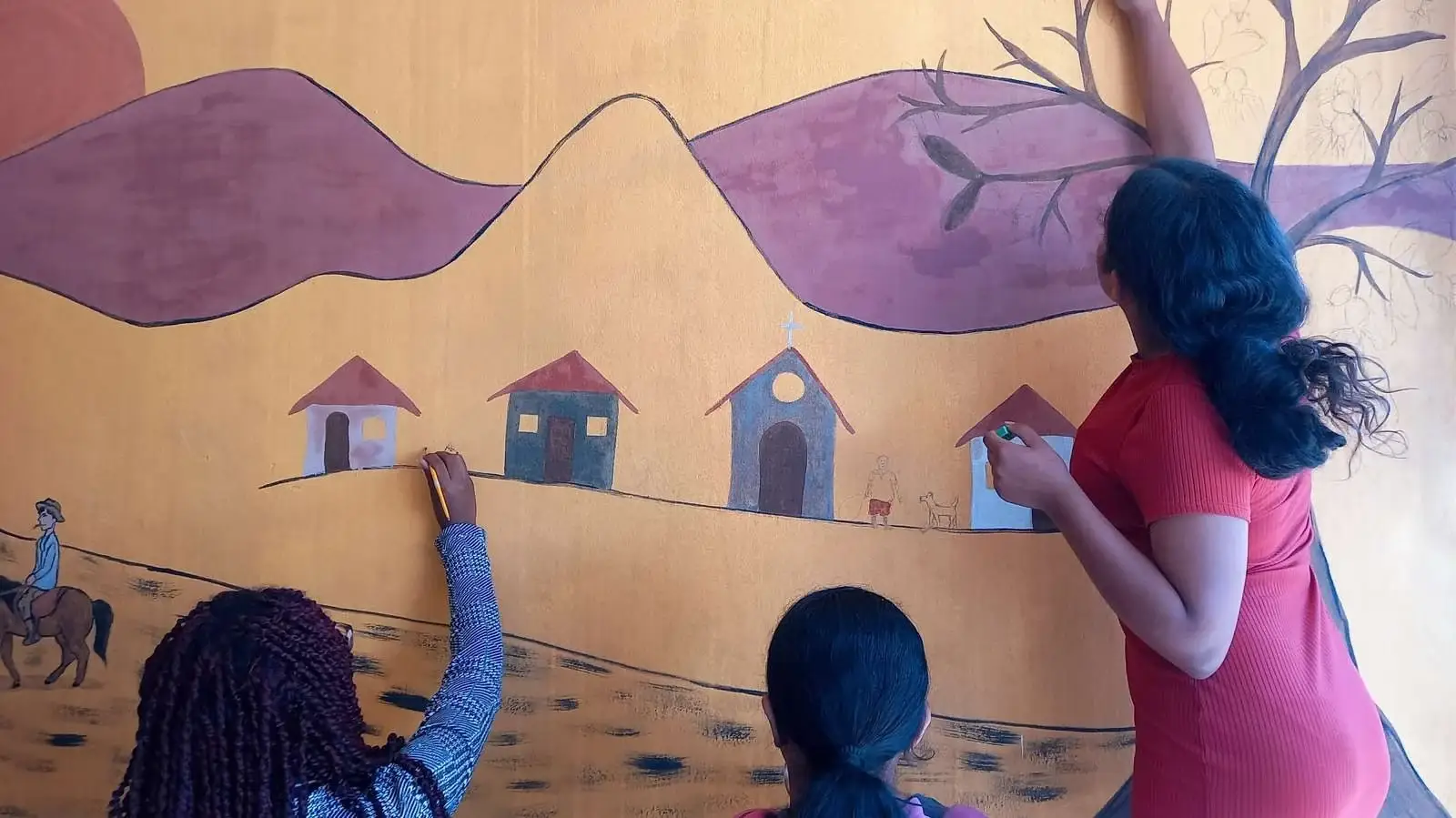 Estudantes pintando mural coletivo com tintas de terra representando a paisagem rural de Mutum, Minas Gerais