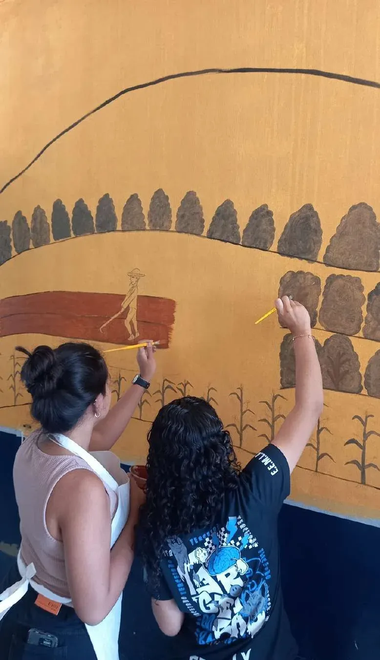 Detalhe do mural de Mutum com estudantes pintando o campo em tons de terra